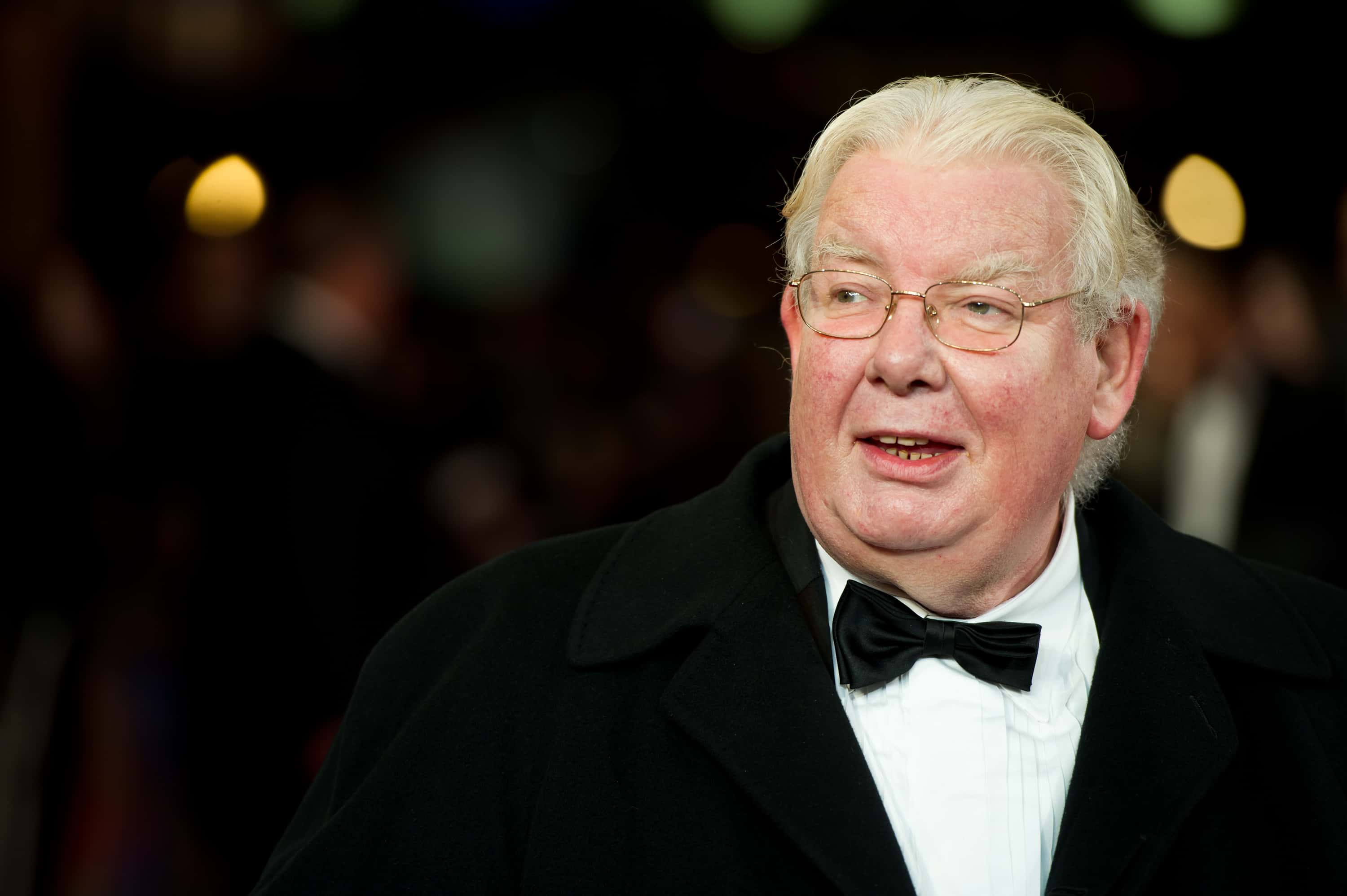Richard Griffiths wearing a black suit