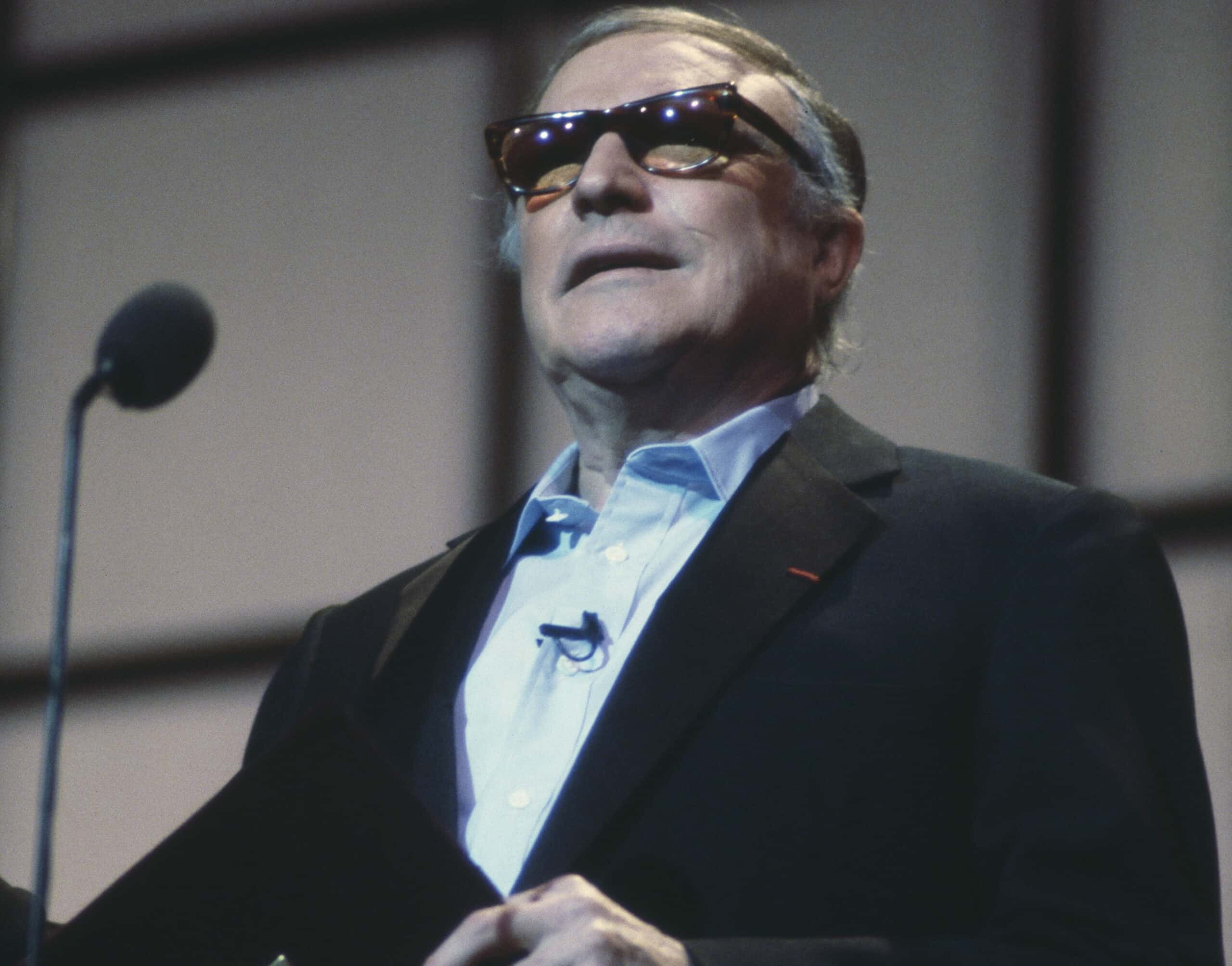 Gene Kelly in suit speaking on mic