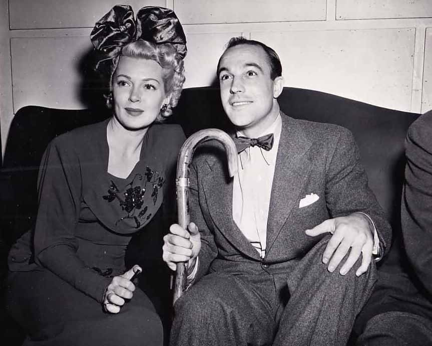 Lana Turner and Gene Kelly sitting on a sofa at an event