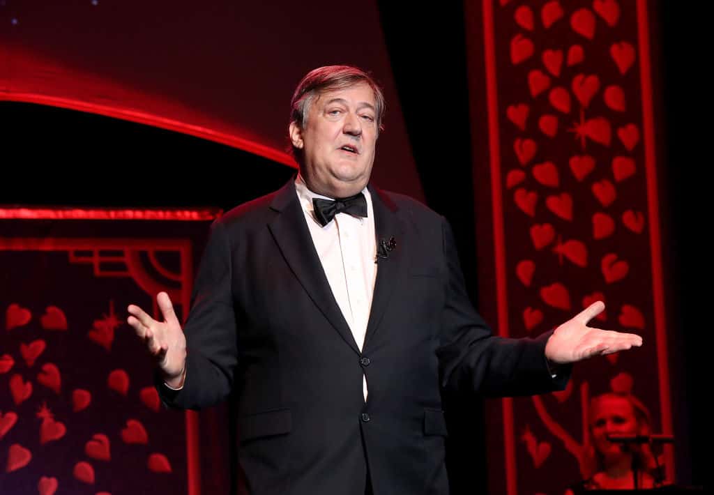 Stephen Fry wearing a black suit