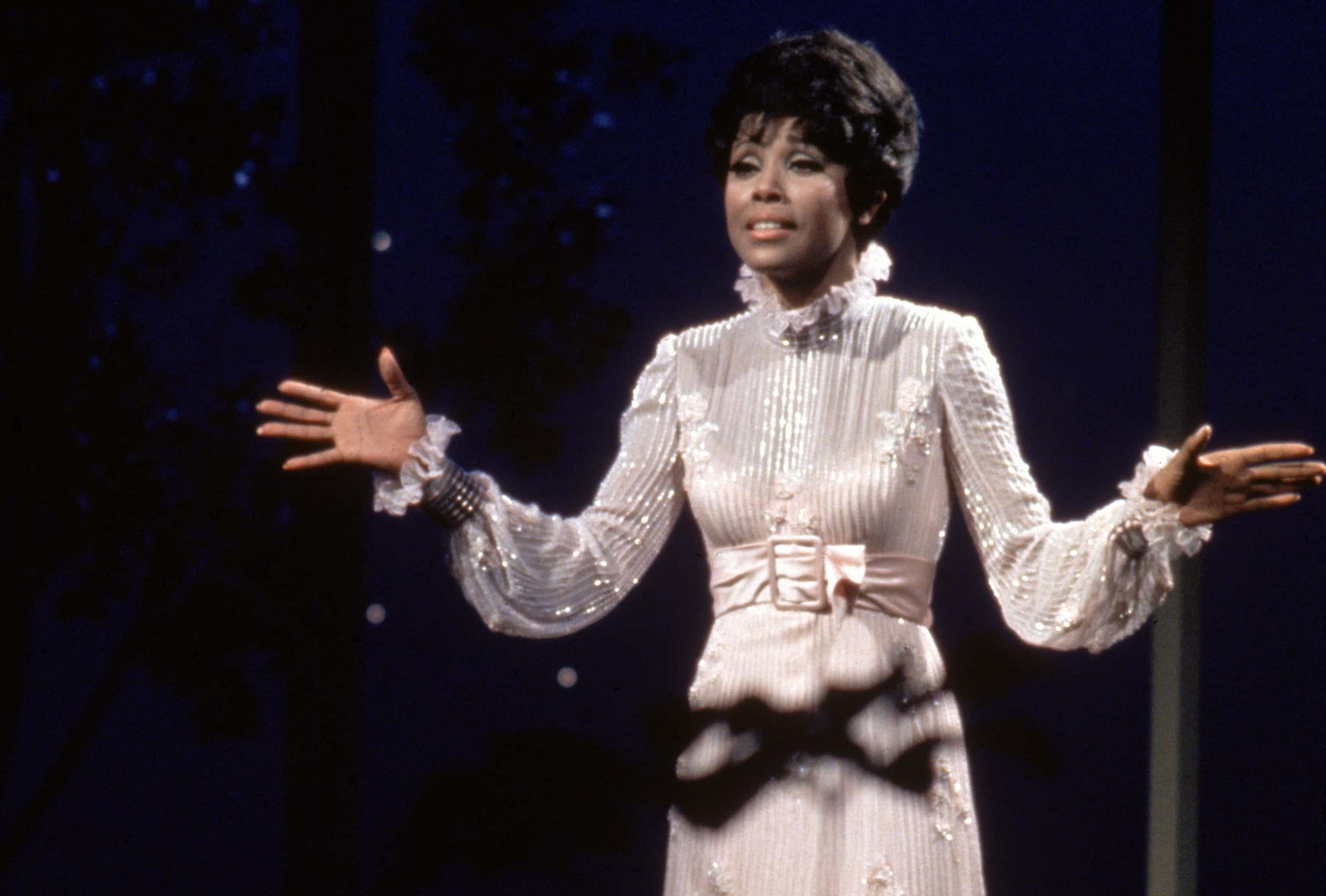 Actress Diahann Carroll performs at a stage wearing white dress