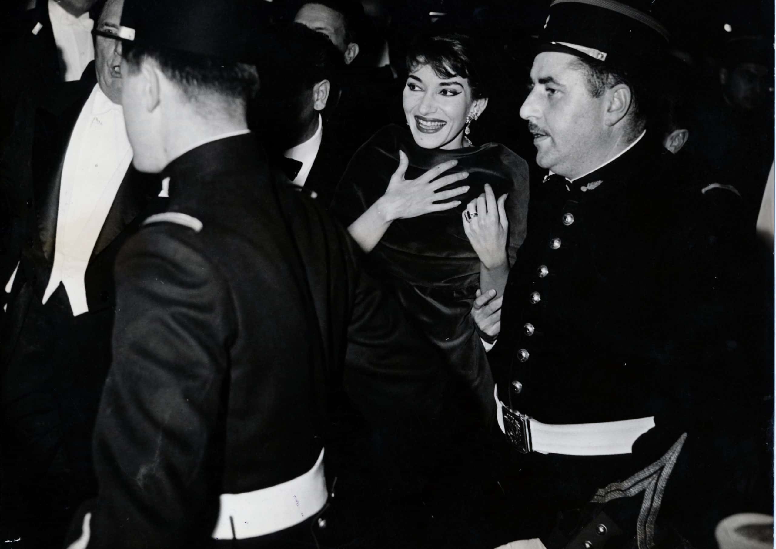 Greek-born American soprano Maria Callas smiling escorted by two policemen. Paris