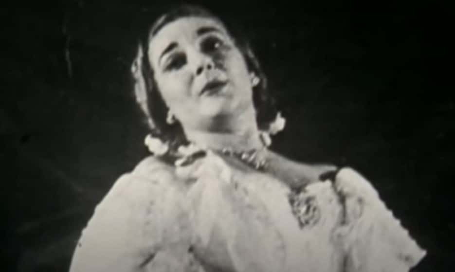 Grayscale Portrait Photo of Maria Callas wearing a white dress, performing on a stage