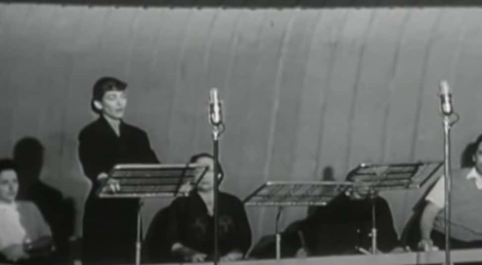 Grayscale Portrait Photo of Maria Callas wearing a black dress, performing on a stage