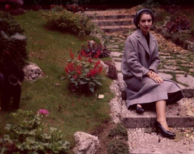 Portrait Photo of Maria Callas wearing gray outfit, sitting on a stairs