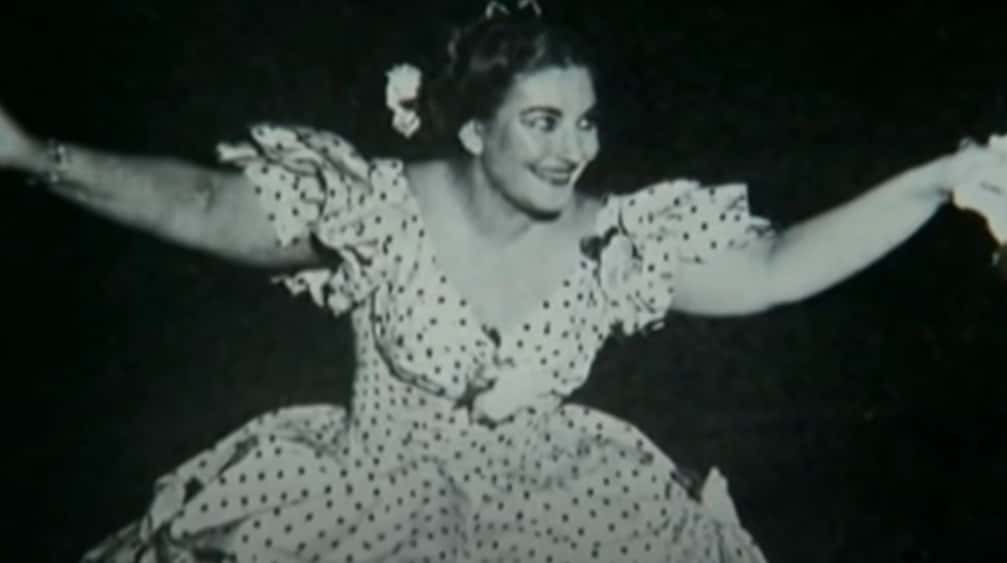 Grayscale Portrait Photo of Maria Callas wearing a white dress, performing on a stage, smiling