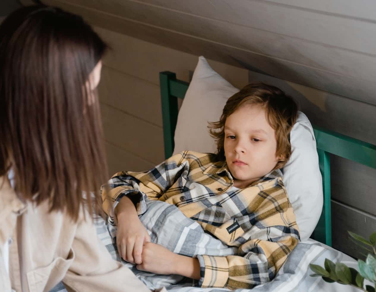 Kid in bed is laying sick.