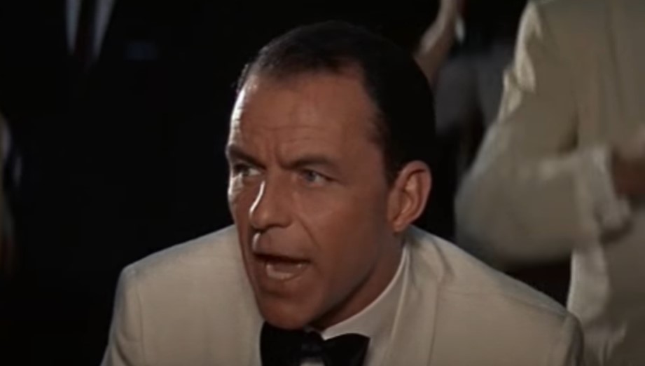 Frank Sinatra in white jacket is looking at side.