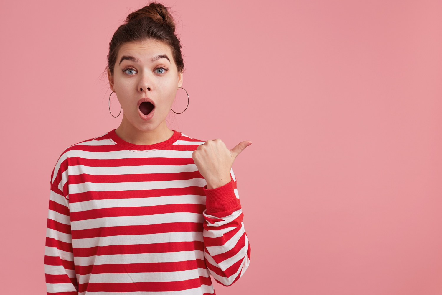 Surprised girl with sweater pointing at side.