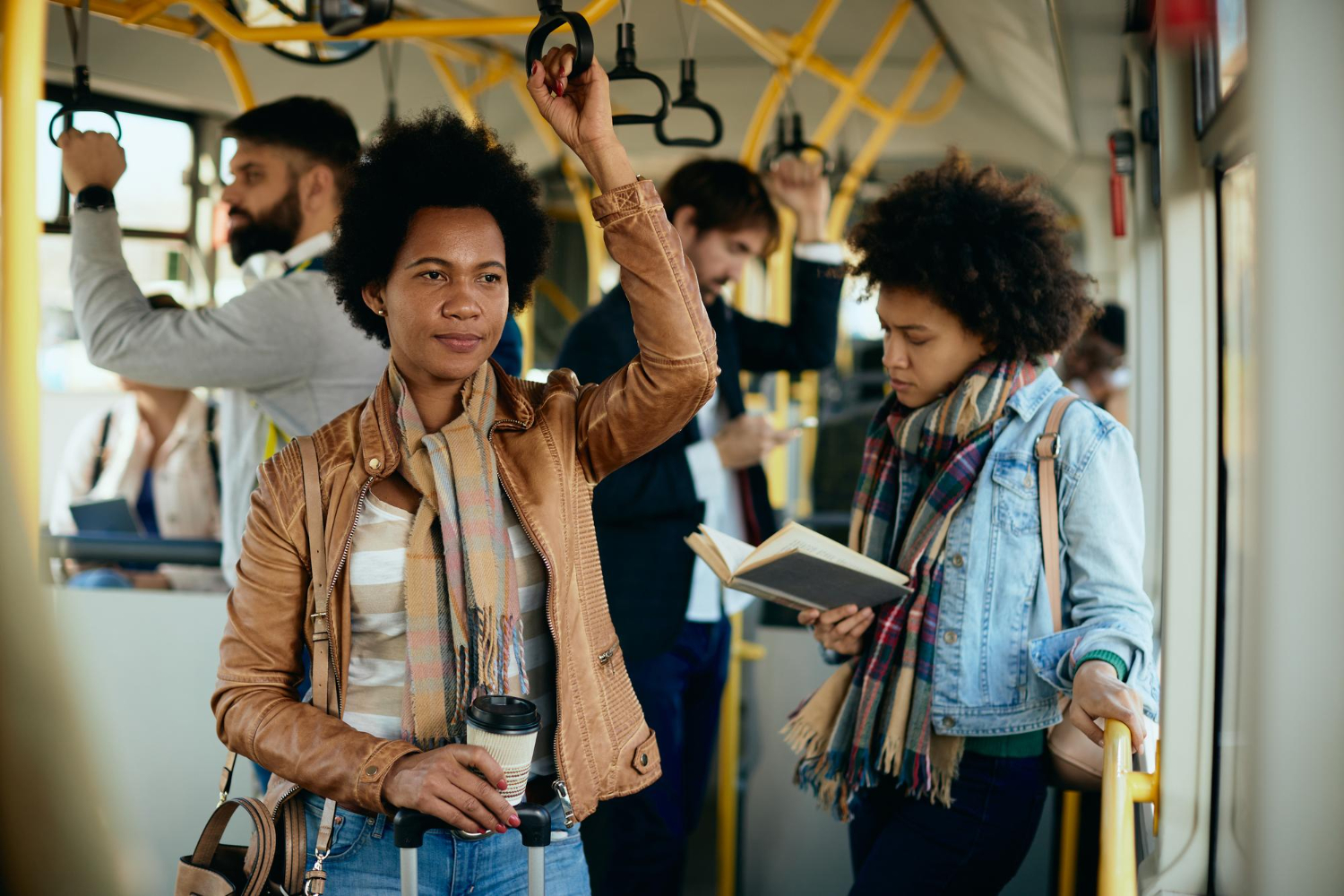 Girl driving in a bus holding coffee in hand.