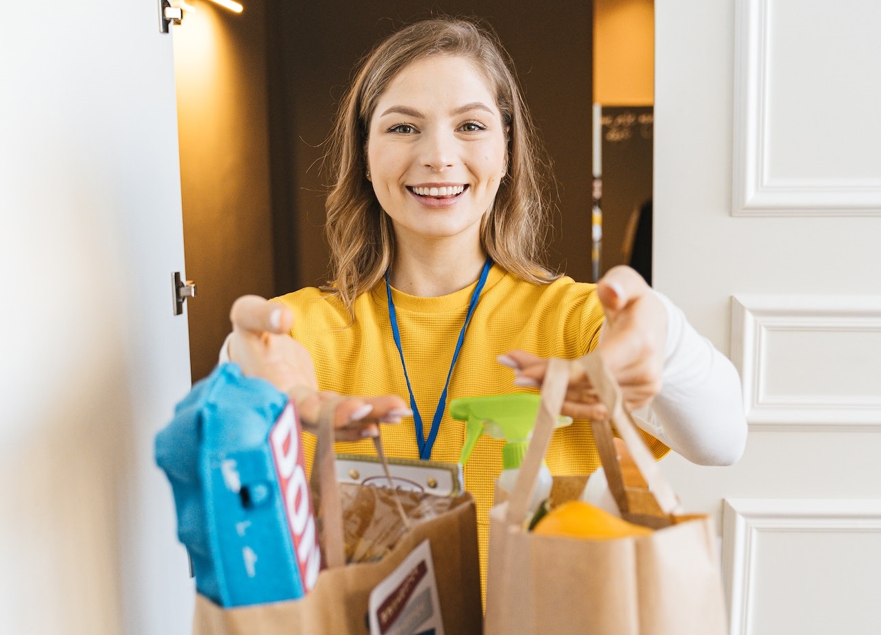 Young woman holding full bag of groceries.