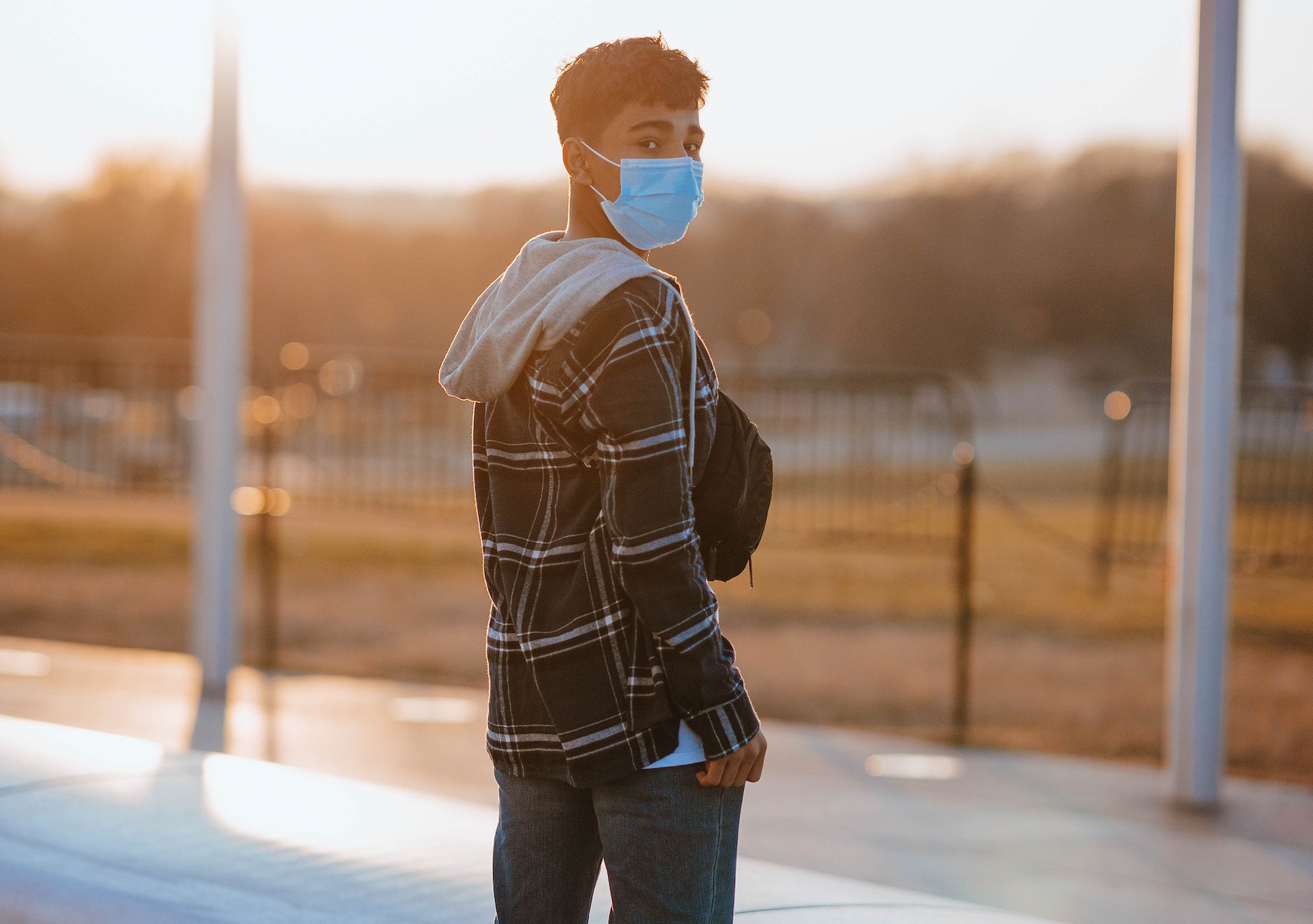 Teenage boy standing in medical mask in street