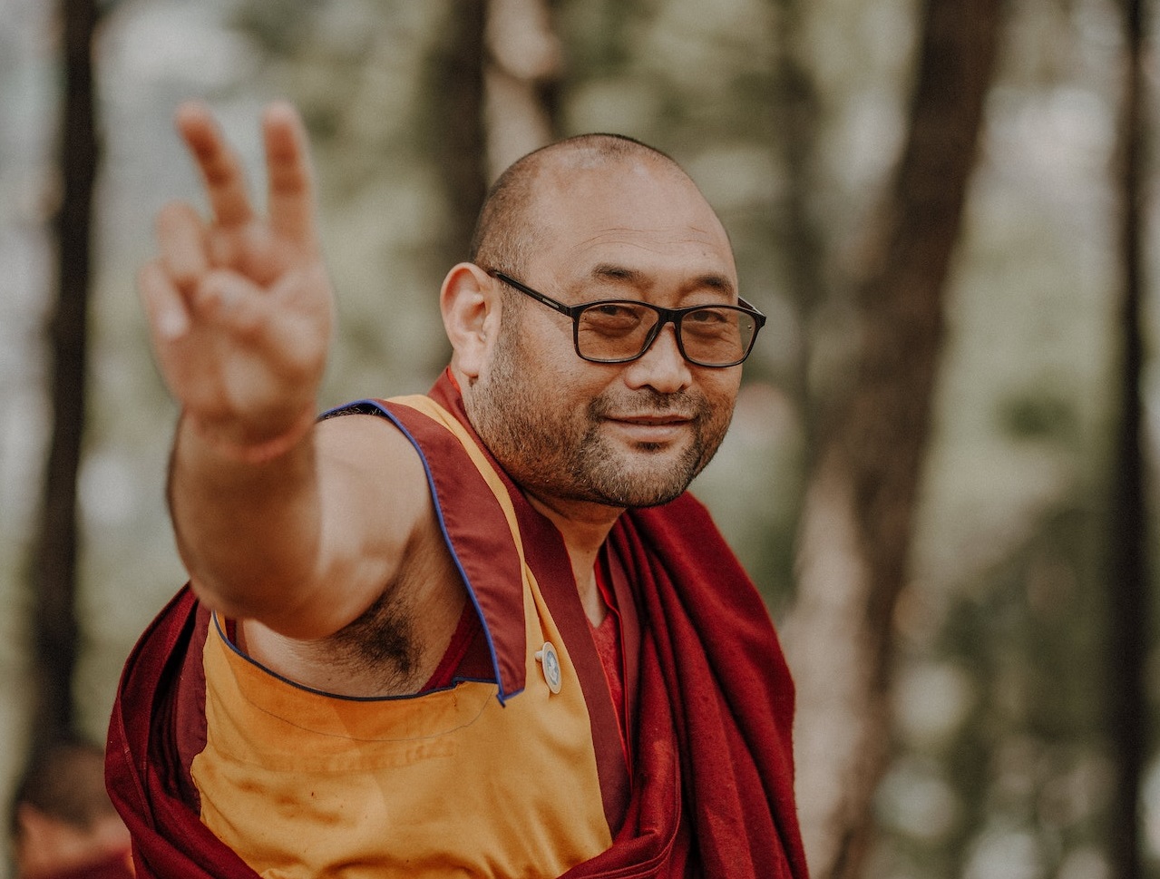 Monk wearing glasses smiling to the camera.
