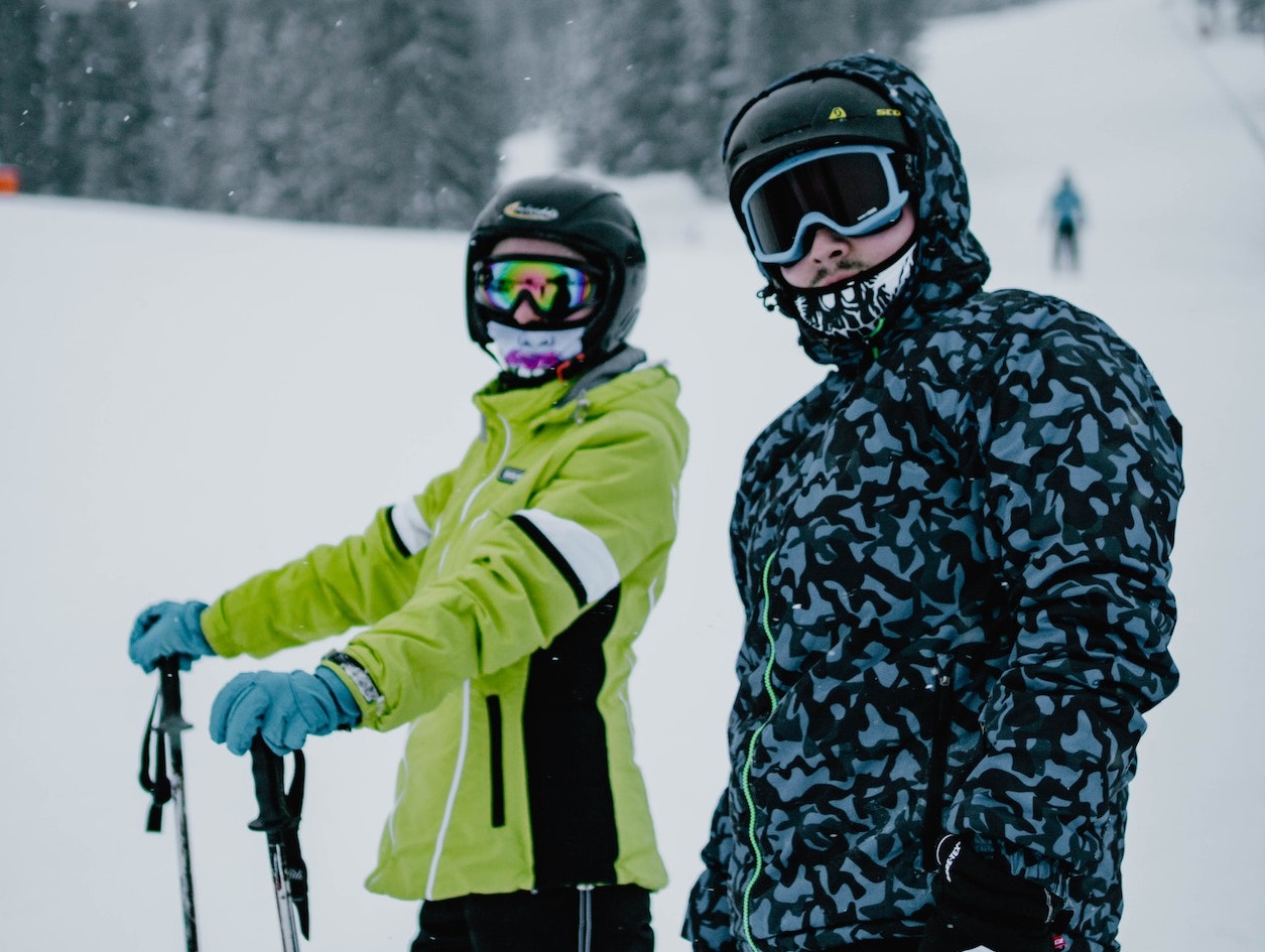 Two young persons wearing winter jackets standing in the snow.