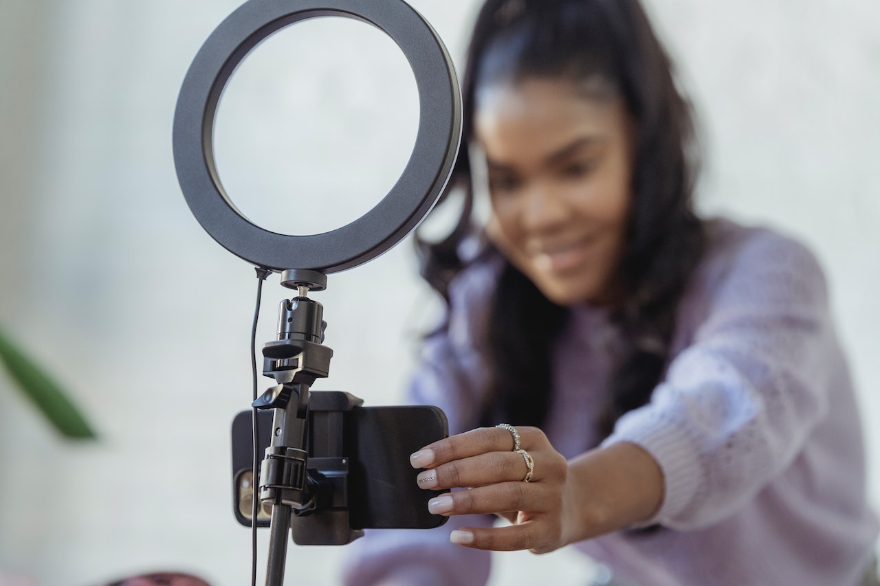Young black woman wearing purple top making a podcast.