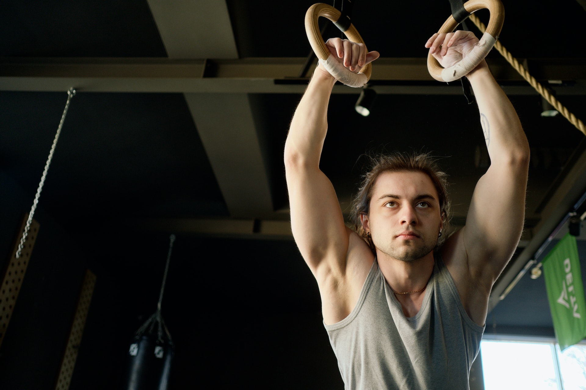 Man in gray tank in gymnastics gym
