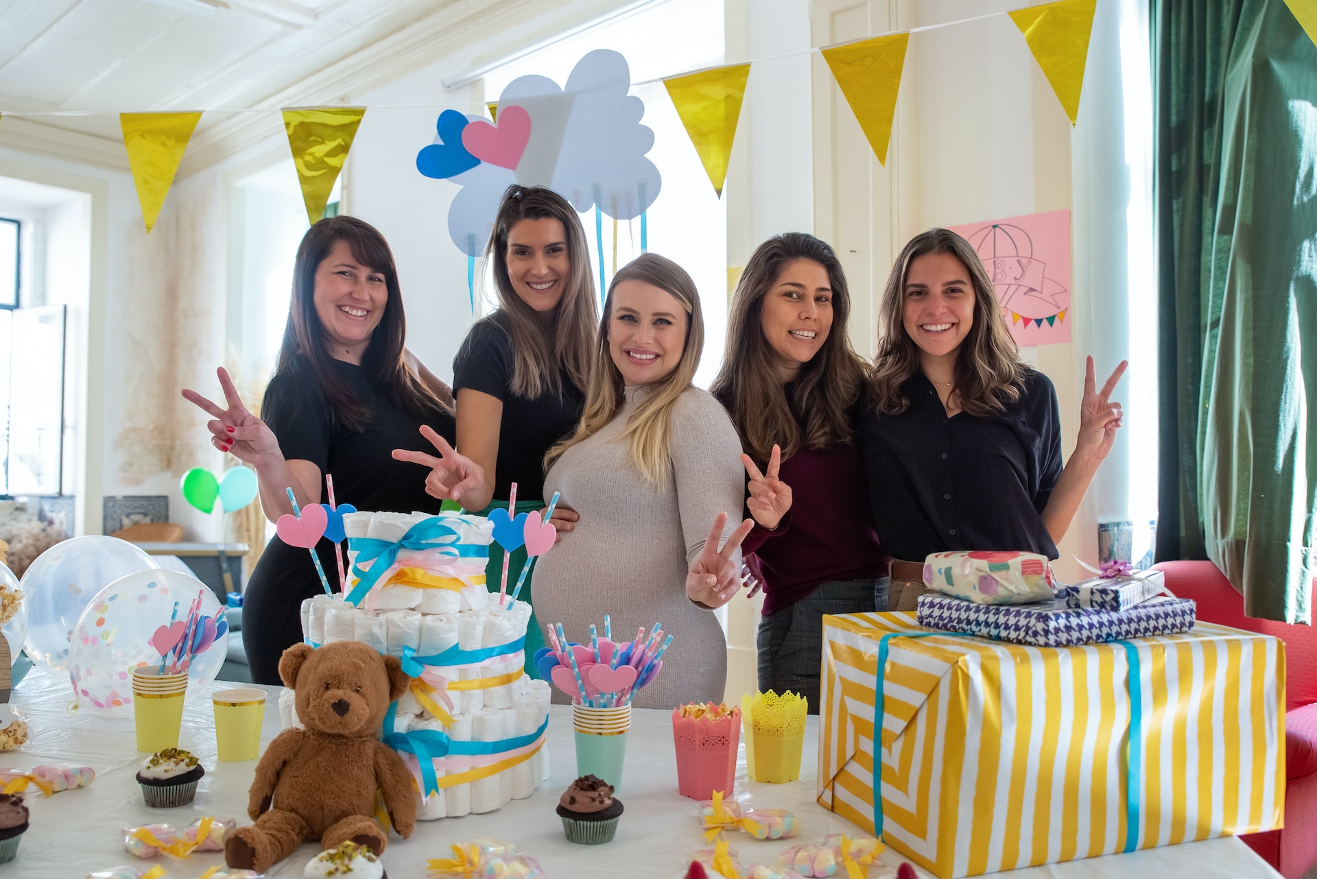 Women at baby shower taking a photo happy behind party decoration