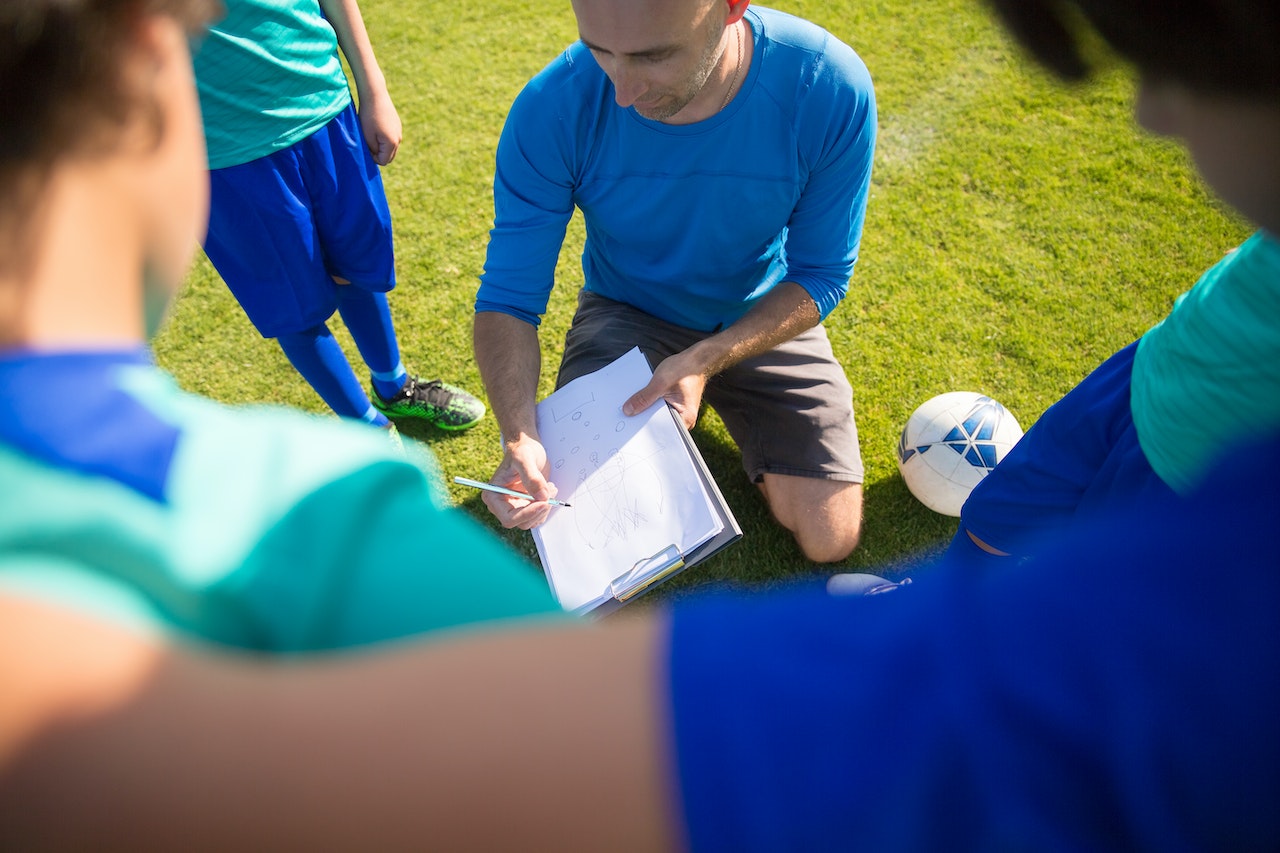 Coach and team having a conversation on the field.