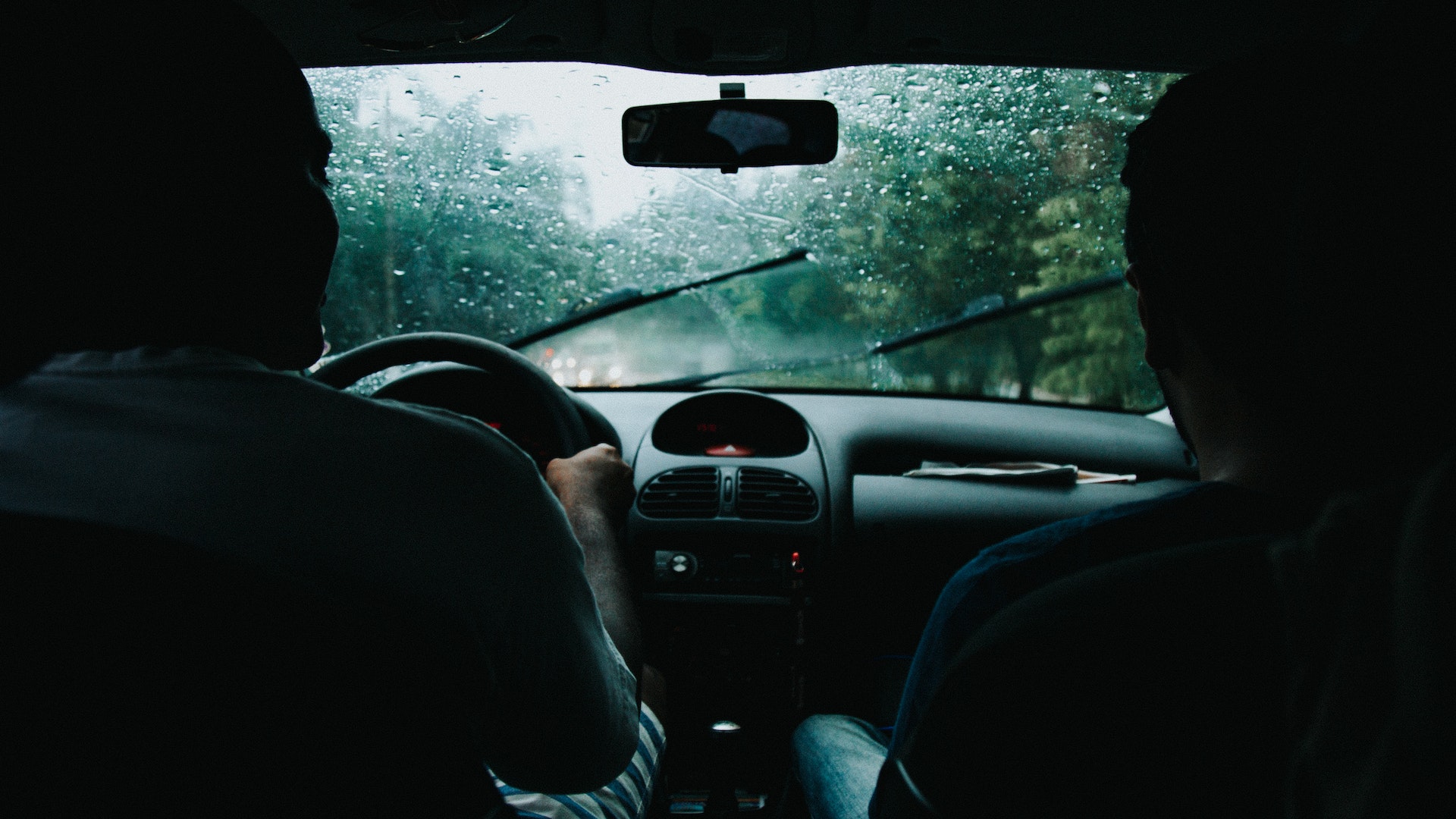 Two men in car driving on a bad weather and rain pouring