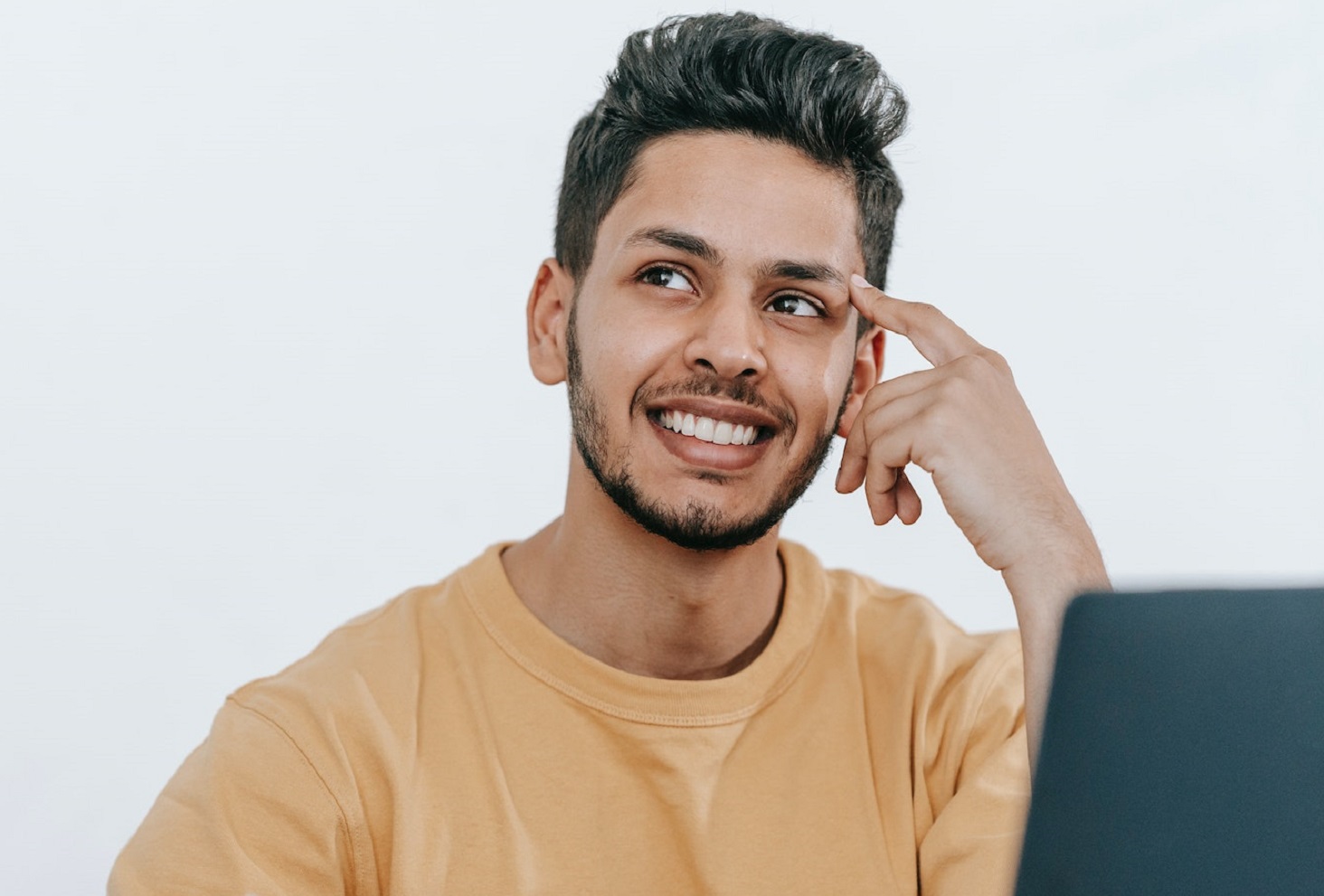 Happy man in yellow shirt thinking and laughing on his desk.
