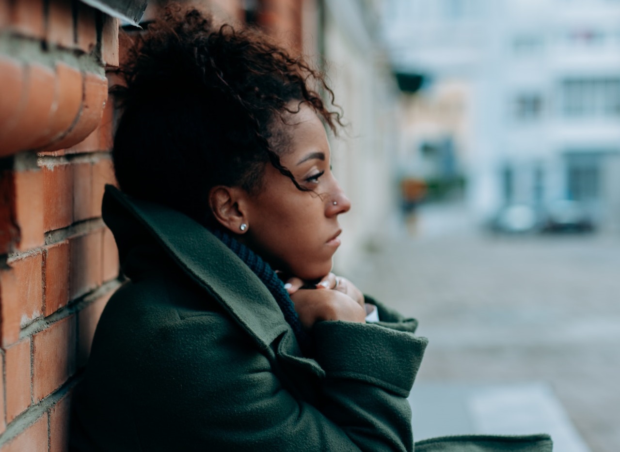 Sad woman in green trench coat thinking