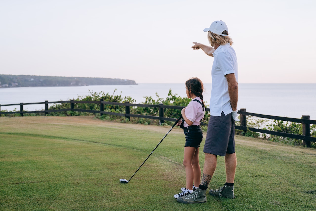 Man and small girl playing golf