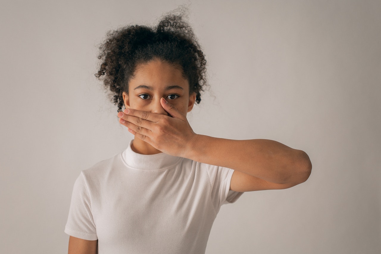 Young girl covering her mouth