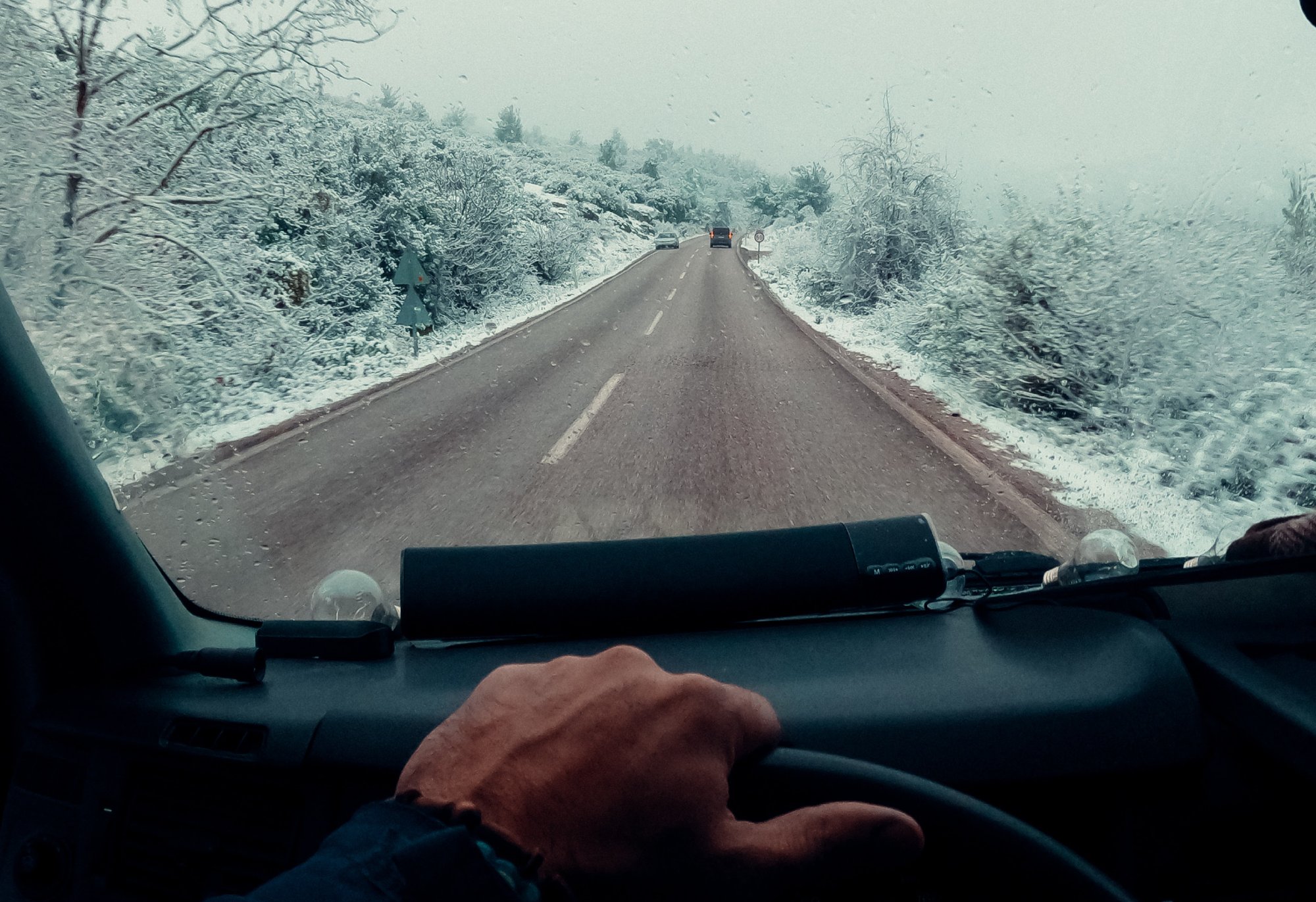 Man at steering wheel driving on road at winter
