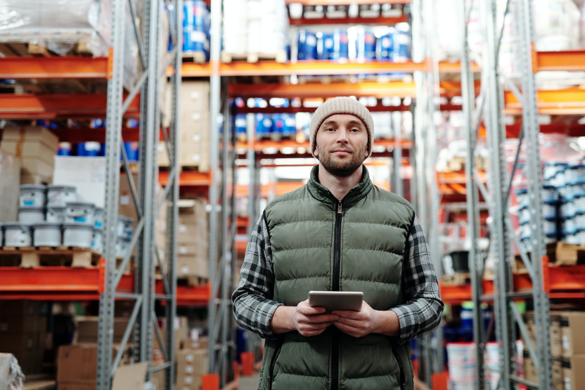 Warehouse manager in bubble jacket holding tablet in warehouse
