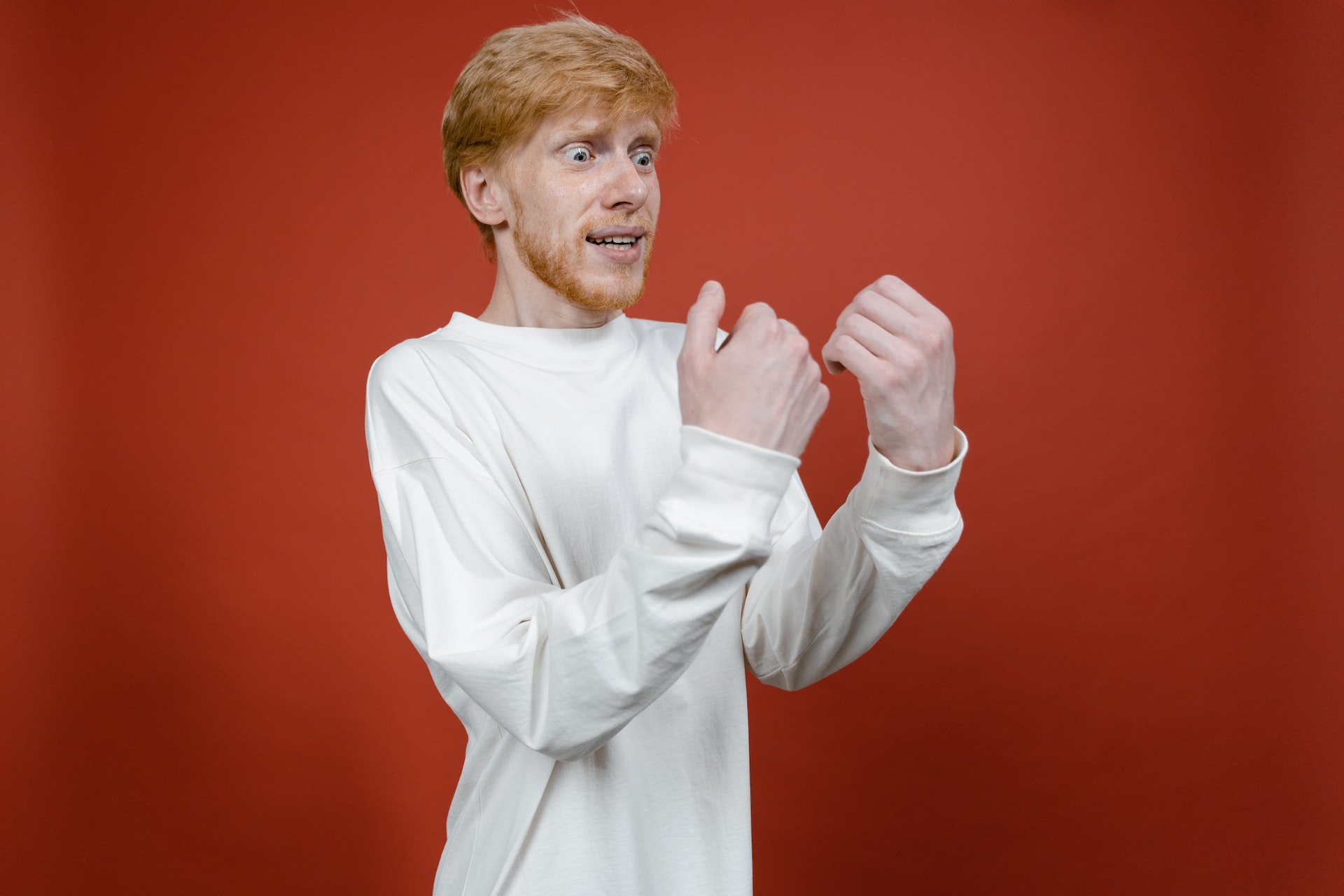 Shocked man with hands in front of him in white sweater