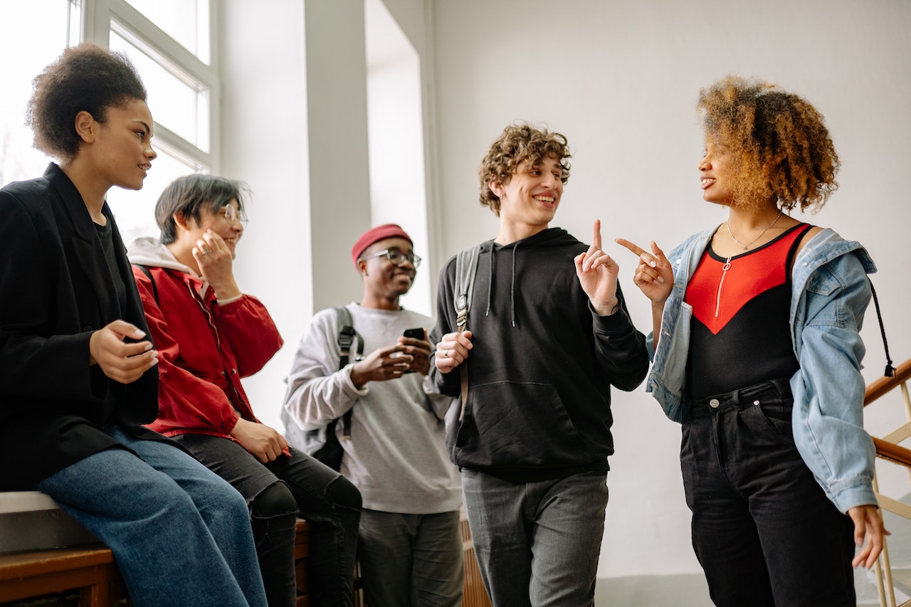 Students talking outside at hallway at school and smiling .