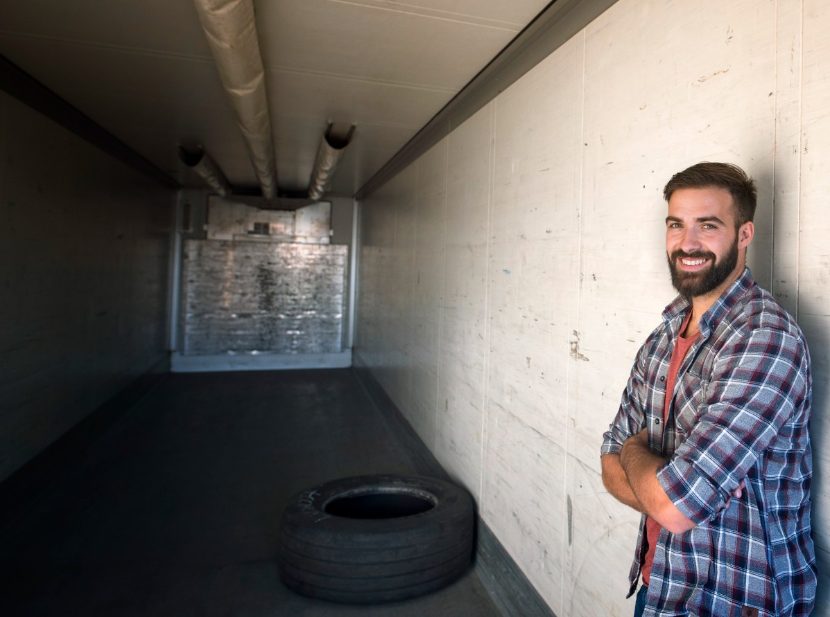 Smiling man with beard seating in empty garage.
