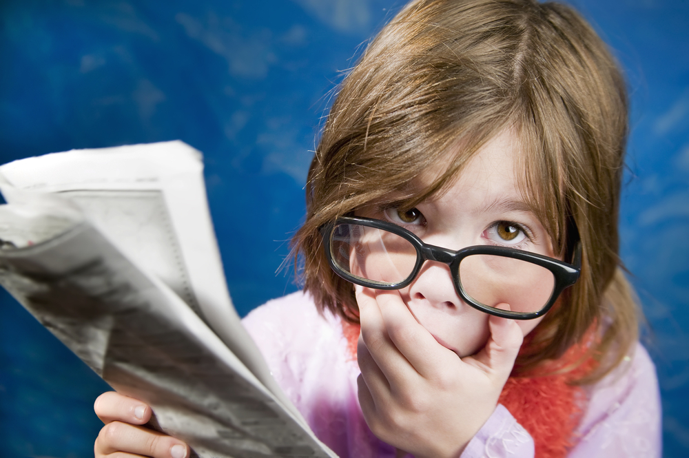 Shocked young girl reading a newspaper