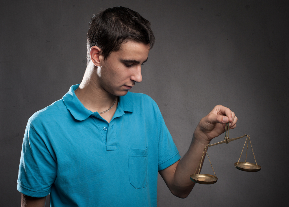 Boy holding a justice scale on a gray background