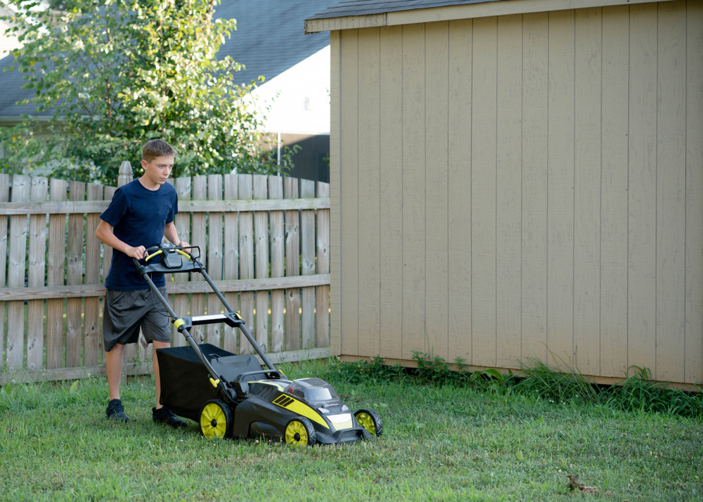 Teenage boy mowing the lawn