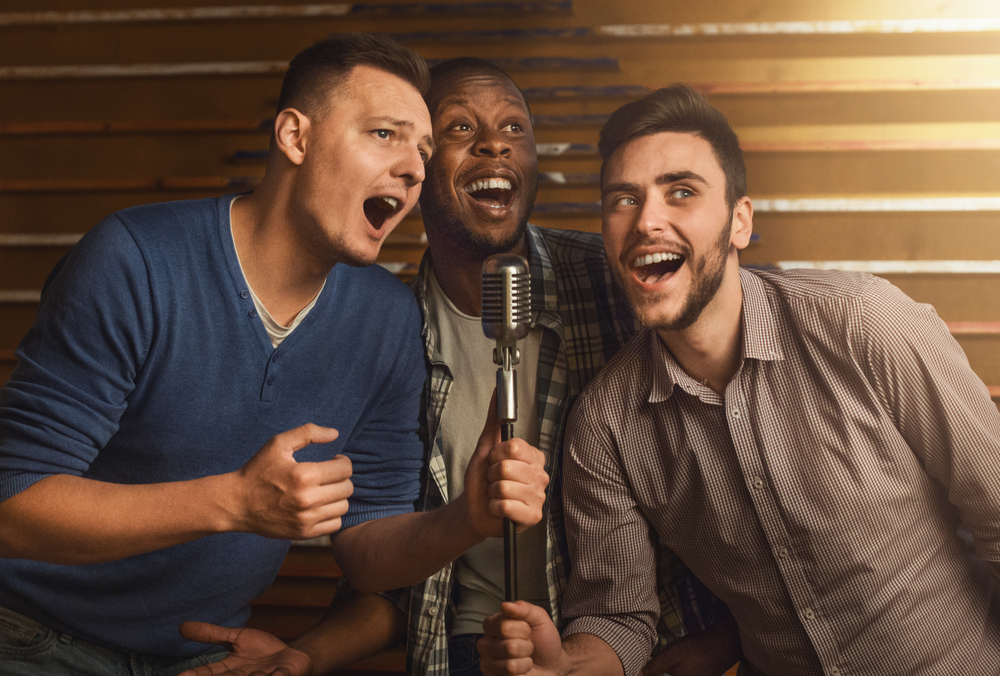 Happy male friends singing karaoke 