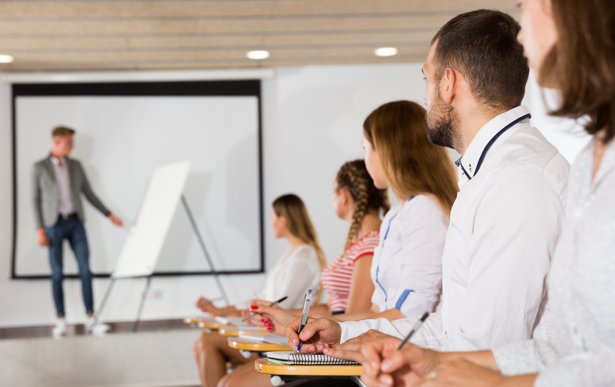 Side view of student wearing white shirt making a speech at class.