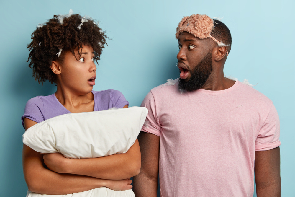  Scared dark skinned woman and man look at each other with shock