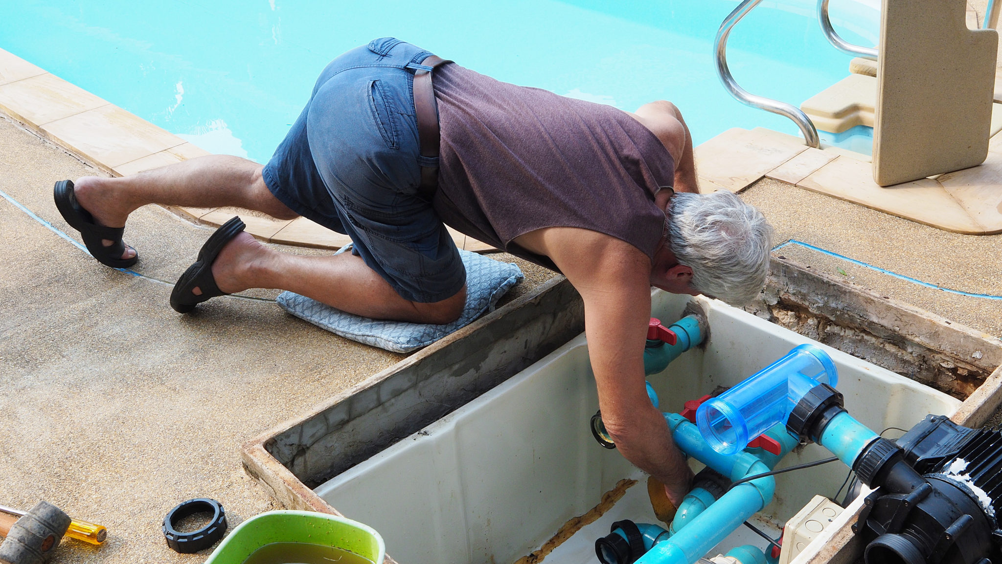 Man cleaning swimming pool pump