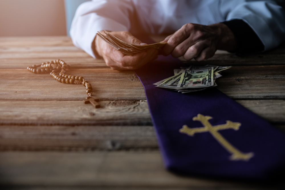 Priest counting money on a wooden table