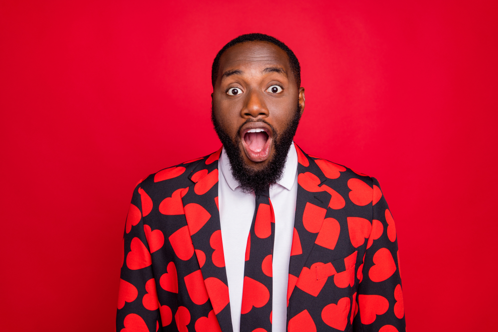 Shocked man at party in heart shapes pattern suit