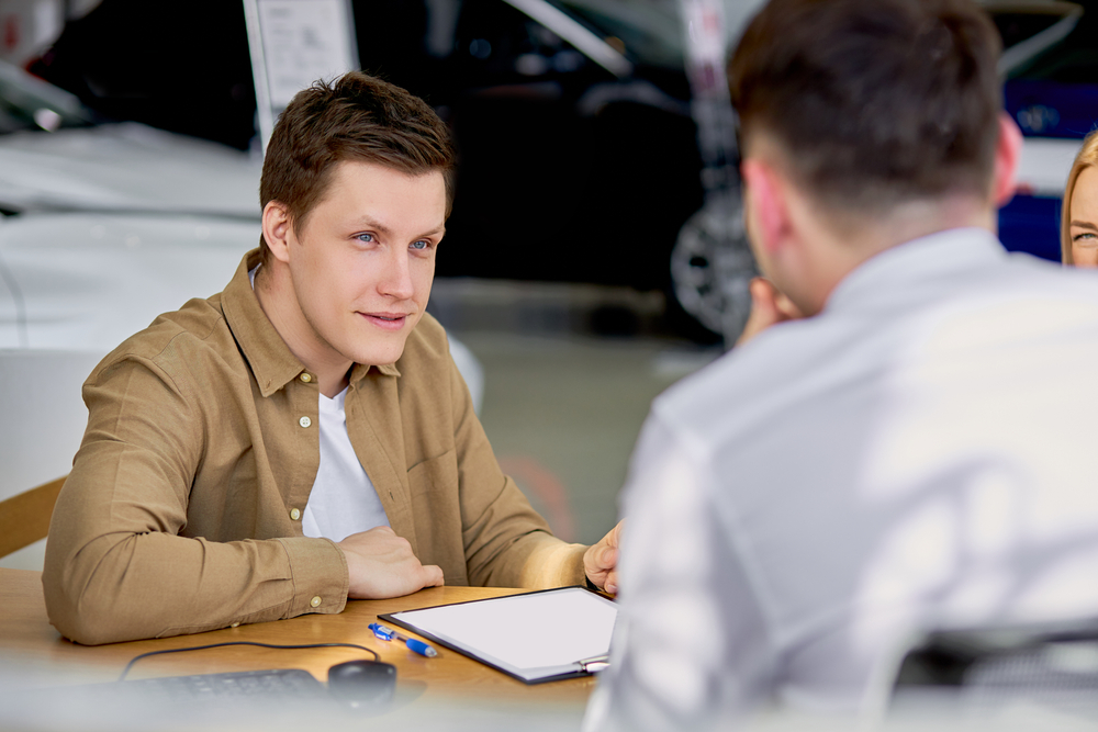 Young employee of car rental place in brown shirt