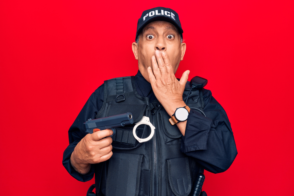 Shocked police officer holding gun 