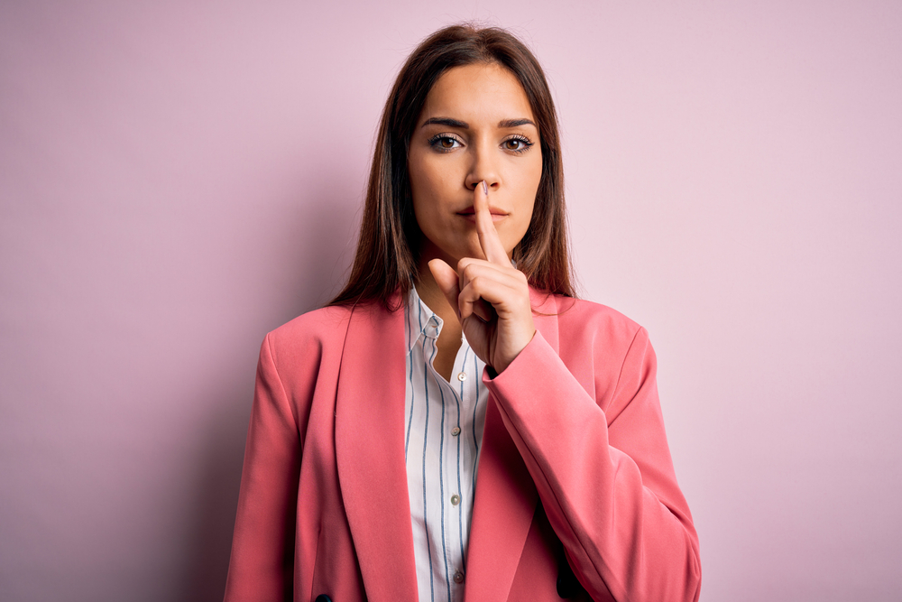 Woman with finger on lips keeping secret 