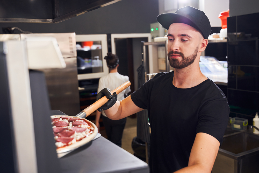 Male chef with beard making a Pizza