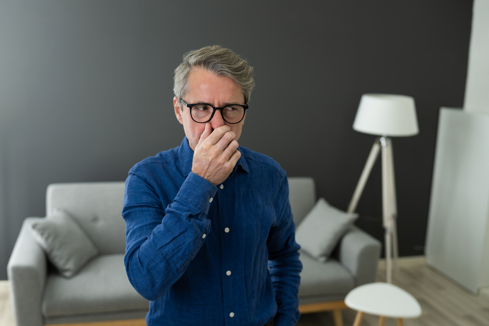 Man holding his nose because of a bed smell