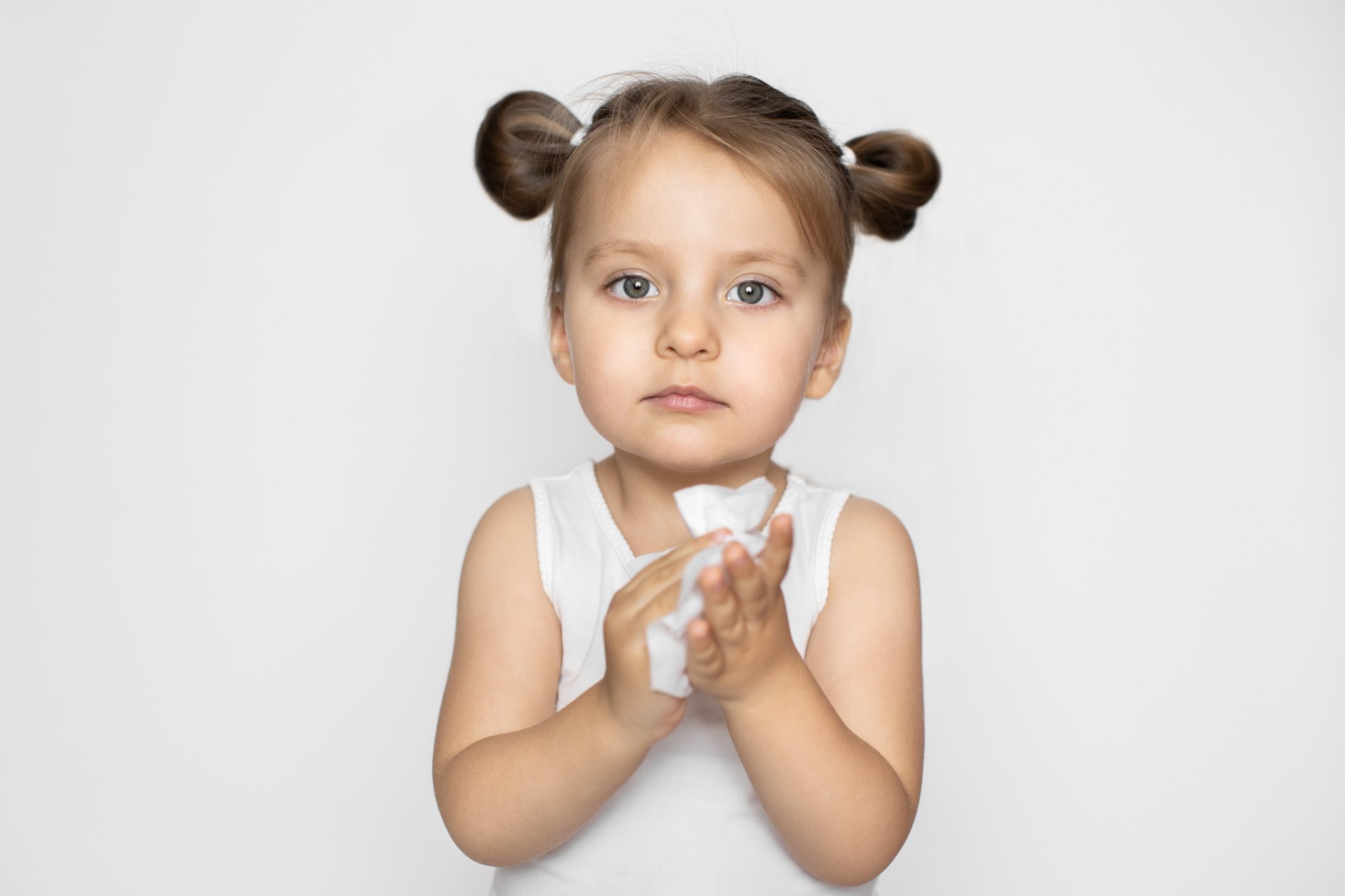 little blonde kid holding a wet wipe in hands.