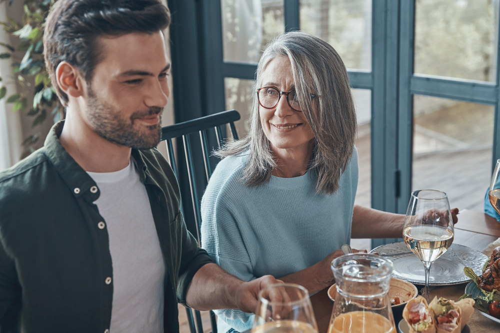 Happy young man having dinner with girlfriend's parents