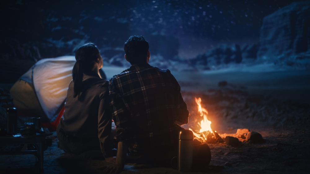 Couple camping watching something in the distance and feeling scared