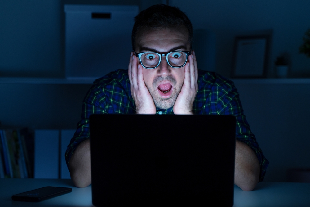Shocked man looking and reading email on laptop